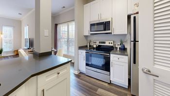 A kitchen with white cabinets and a stove and a microwave